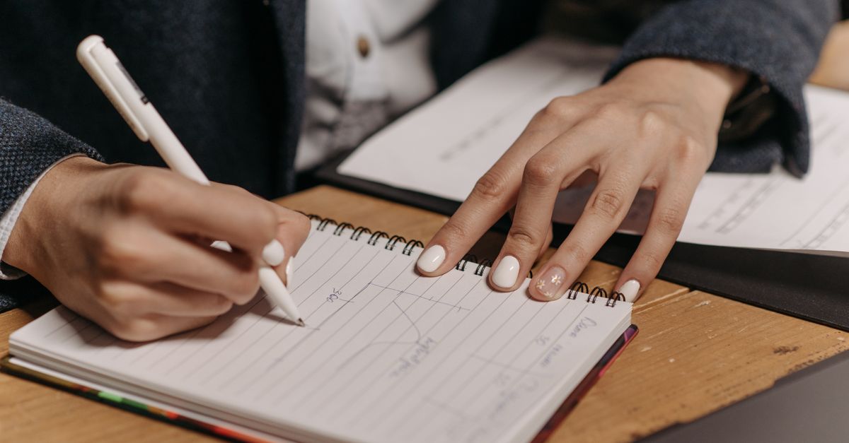 Close up of hands writing dates in a spiral notebook