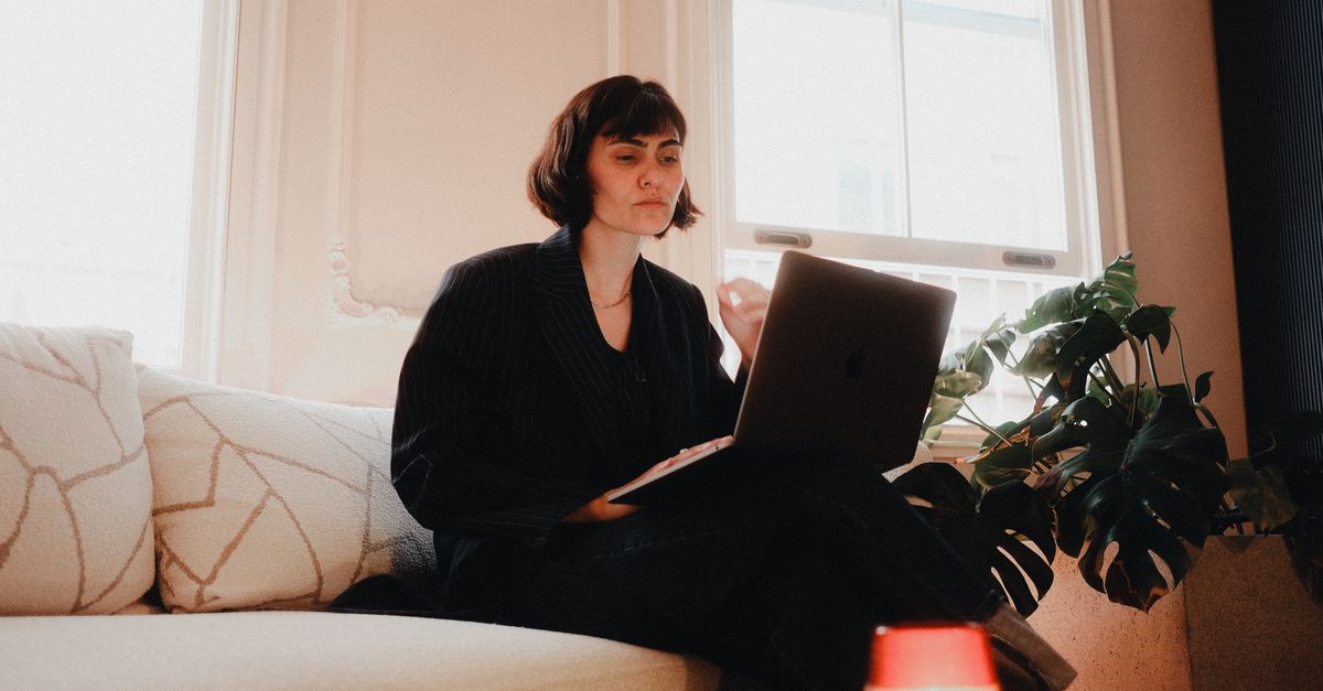Woman working on a laptop on a sofa at home