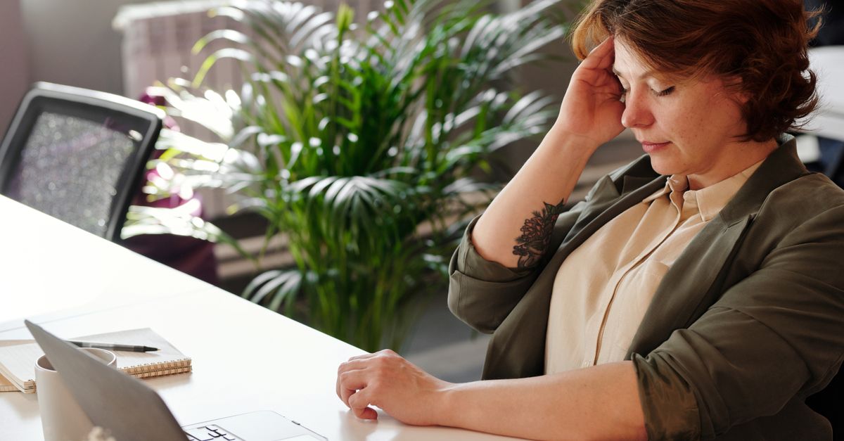 Woman in her forties at an office desk in daylight, drained after perimenopause night waking