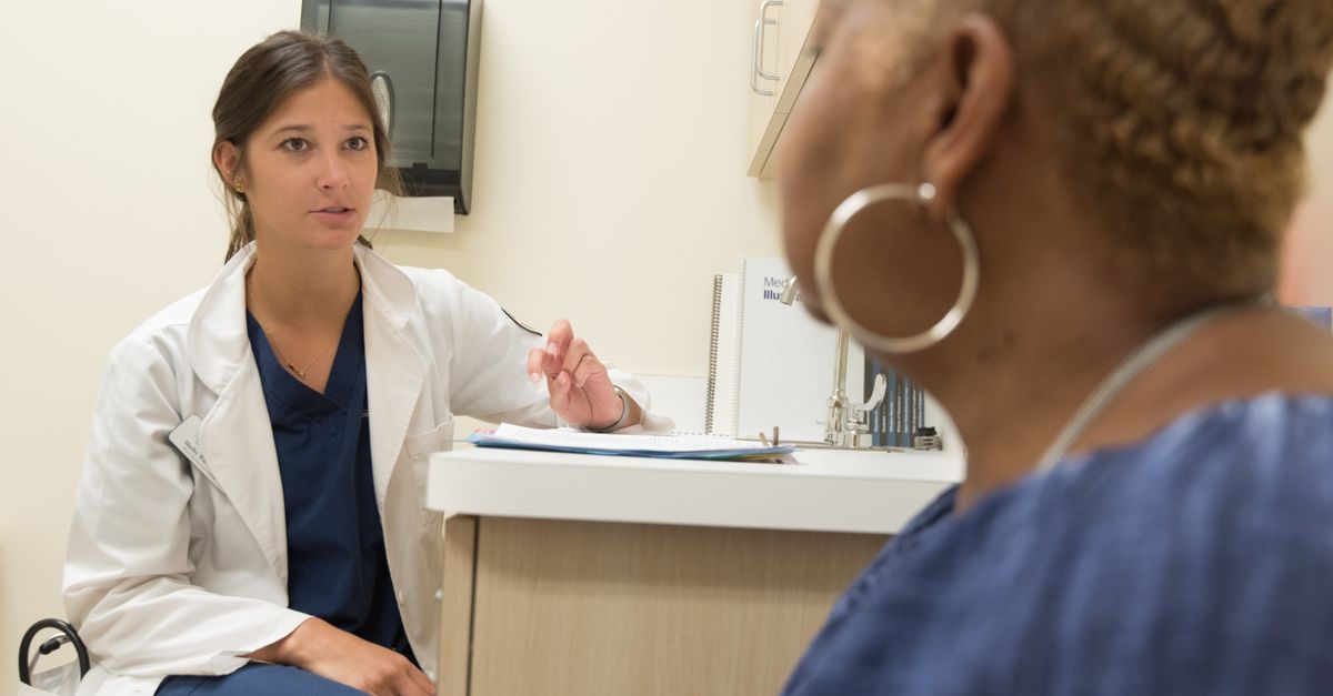 Doctor at a desk talking with a woman patient about breast pain during perimenopause