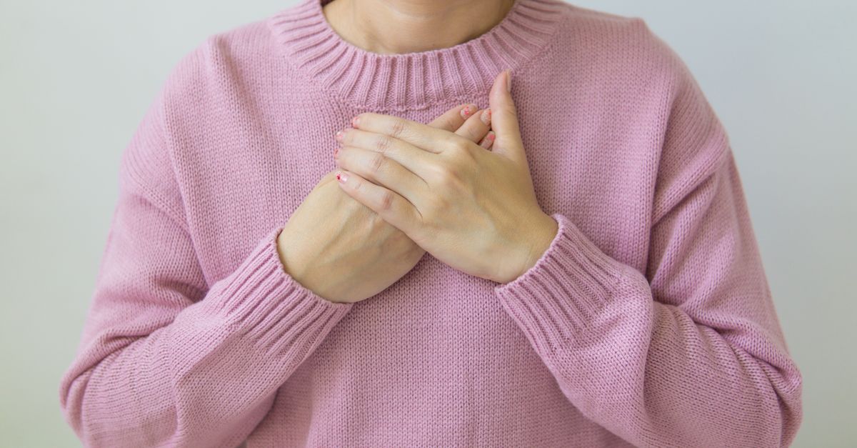Close up of a woman's hands folded across her chest, where perimenopause breast pain is felt