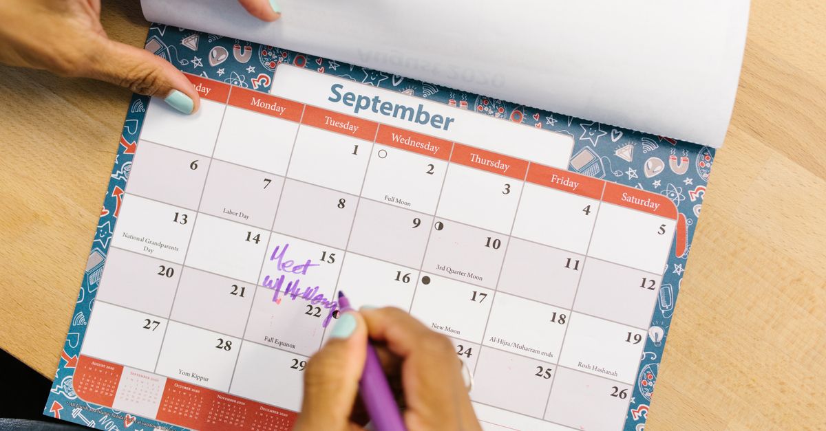 Hand marking dates on a wall calendar with a purple pen to track perimenopause cycle changes