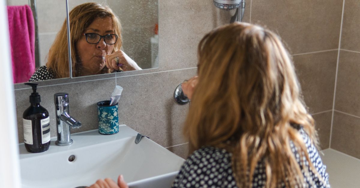Woman at a bathroom mirror in the morning, checking skin after a night of perimenopause itching