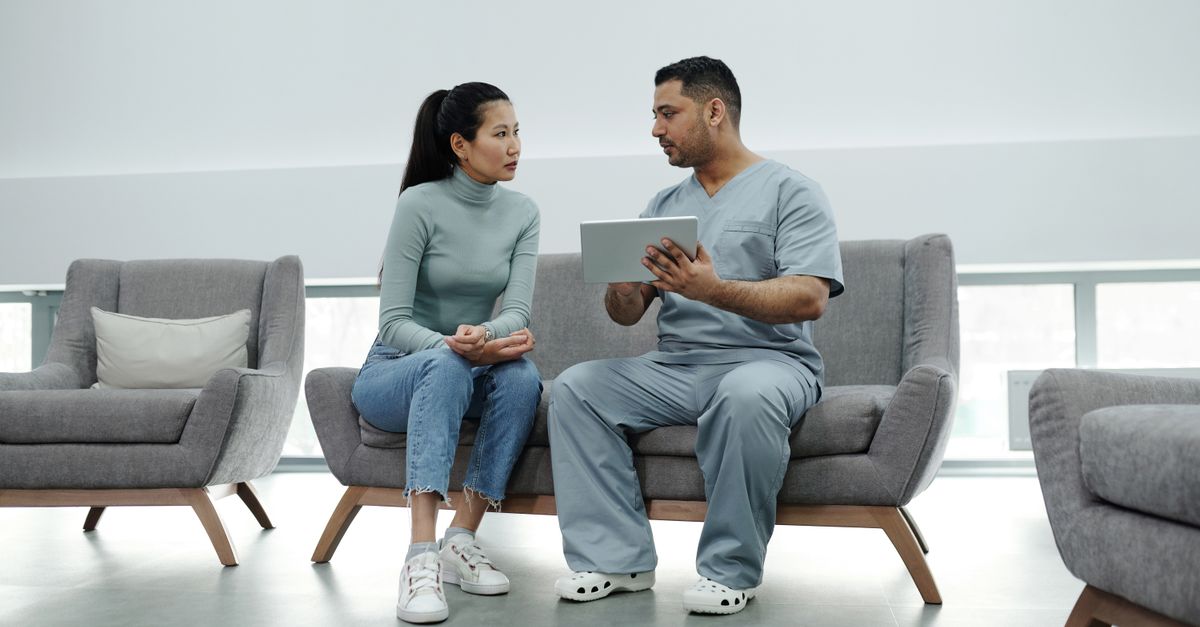 Woman talking with a clinician about perimenopause joint pain while they look at notes together