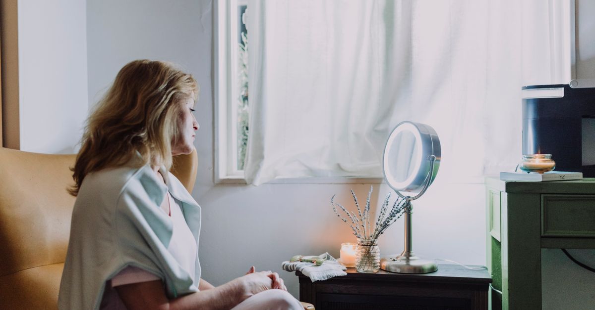Woman in her forties sitting quietly at a dressing table at home