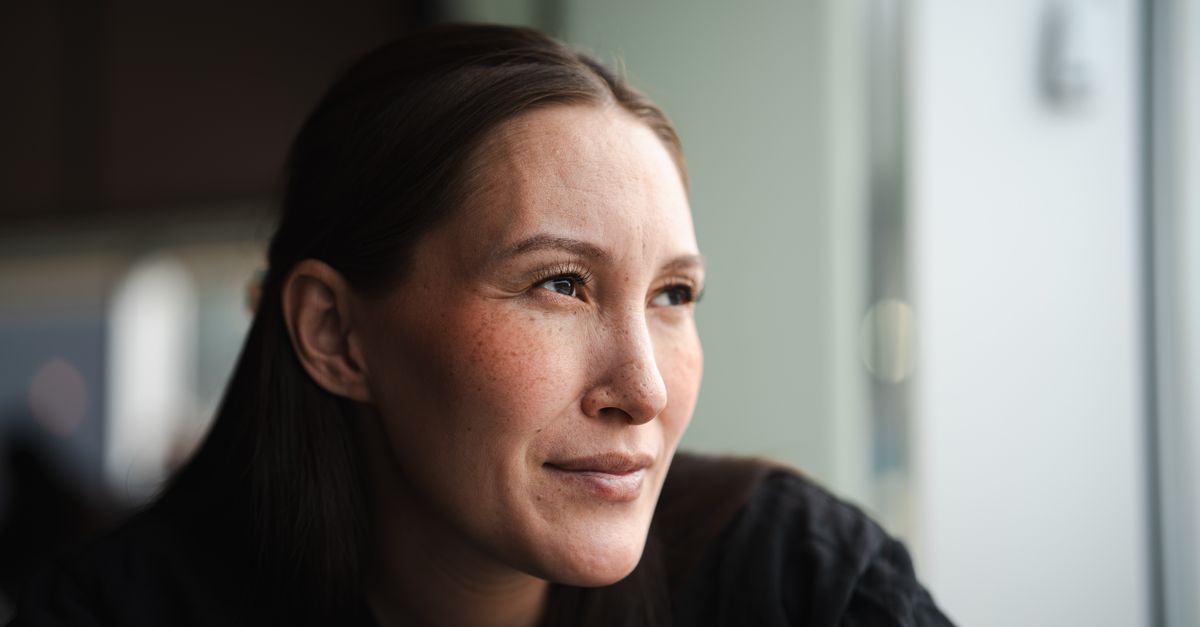 Woman in her forties looking out of a window, thinking about why perimenopause symptoms come and go