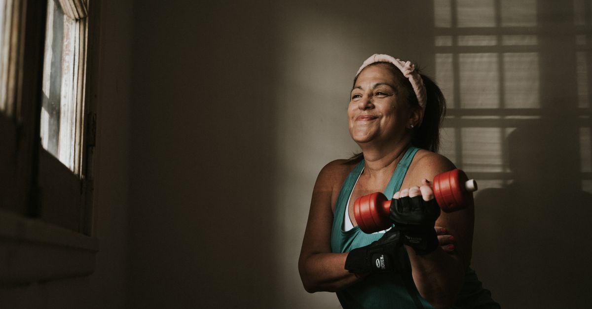 Middle aged woman lifting dumbbells indoors during the years bone loss accelerates around menopause